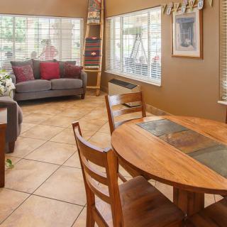 A cozy living and dining area featuring a comfortable sofa, wooden dining table with chairs, and large windows letting in natural light.