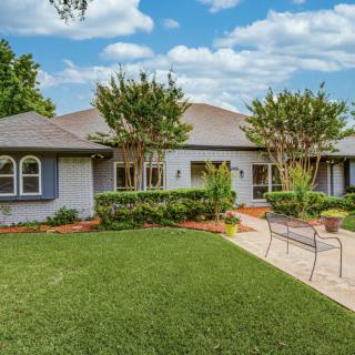 A well-maintained residential house with a lush front yard and landscaped garden.