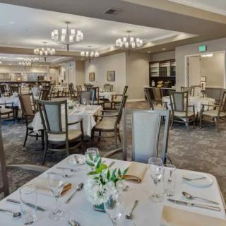 An elegantly set dining room with tables and chandeliers.