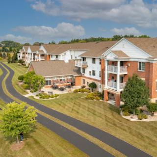 A scenic view of a residential apartment complex surrounded by lush greenery and a winding road.