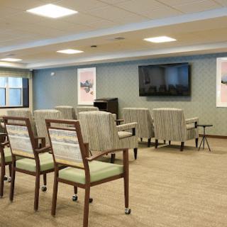 A modern waiting area featuring comfortable chairs and a large television.