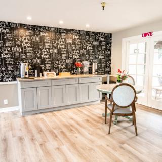 A modern kitchen interior with a coffee station, featuring a stylish black and white wallpaper and light wood flooring.