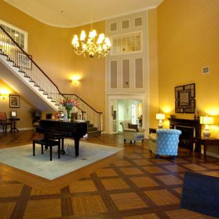 An elegant living room featuring a grand piano and staircase.