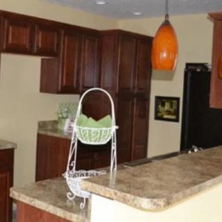 A kitchen featuring wooden cabinetry, a marble countertop, and an orange pendant light.