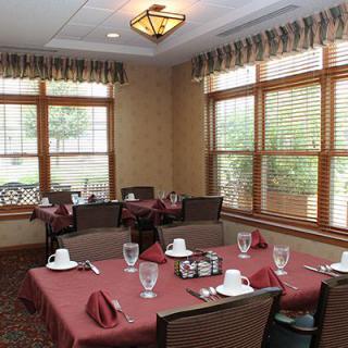 A well-arranged dining area with tables set for a meal, featuring large windows and natural lighting.