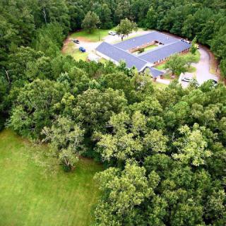 Aerial view of a building surrounded by dense forest and greenery.