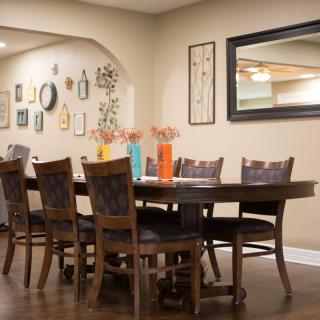 A cozy dining room setup with a wooden table and chairs, adorned with colorful vases and surrounded by wall decorations.