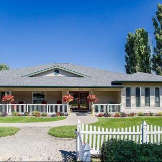 A single-story house with a manicured front yard and a white picket fence.
