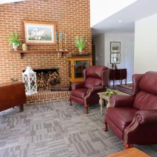 A cozy living room featuring a brick fireplace, leather armchairs, and traditional decor.