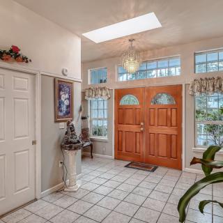 A well-lit entryway with a wooden front door, tiled floor, and tasteful decorations.