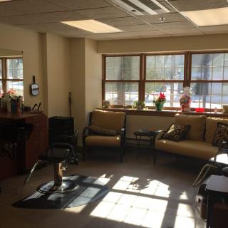 A cozy waiting room with sunlight streaming through the windows, featuring comfortable seating and a coffee table.
