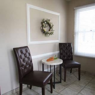 A cozy corner with elegant chairs and a decorative wreath on the wall.