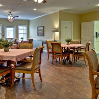 A cozy dining room with neatly arranged tables and chairs, featuring warm lighting and decorative elements.