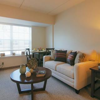 Cozy living room with a sofa, coffee table, and a dining area by the window.