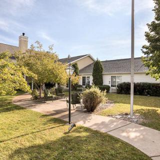 A residential building with a well-maintained lawn and pathway, surrounded by trees and featuring a flagpole.
