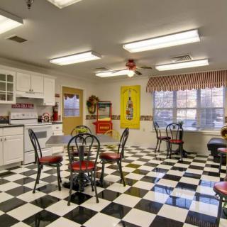 A retro-style kitchen with a checkered black and white floor, decorated in diner fashion.