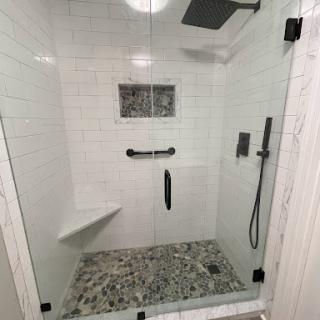 A modern, stylish shower featuring a glass enclosure and elegant tile work.