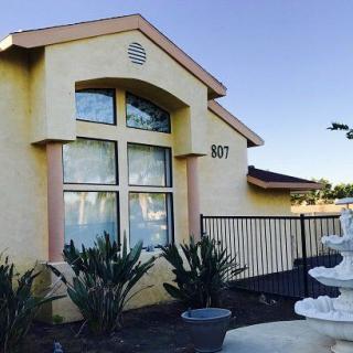 A charming residential house with large windows and a fountain in the front yard.
