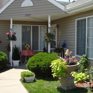 A cozy front porch surrounded by a well-maintained garden with colorful flowers and plants.
