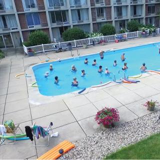 A group of people enjoying a swim in an outdoor pool at an apartment complex.