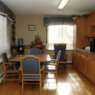 A cozy kitchen and dining area with wooden cabinets, a table set, and natural light streaming in through the window.