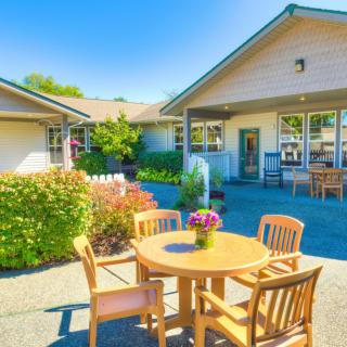 A sunny outdoor patio area with wooden furniture and landscaped garden.