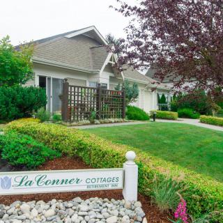 A well-maintained house with a lush garden and a sign reading 'La Conner'.