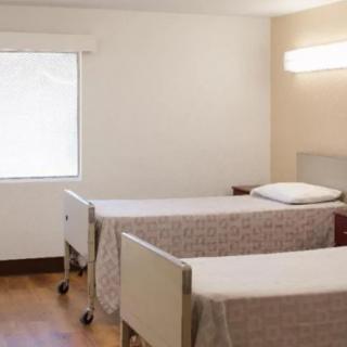 An empty hospital room with two neatly made beds and minimalistic decor.