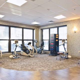 A well-lit rehabilitation room with stationary bikes and large windows.