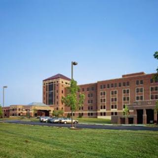 A modern hospital building surrounded by green grass and a clear blue sky.
