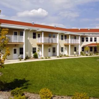 A two-story residential building with a well-maintained lawn and balconies.