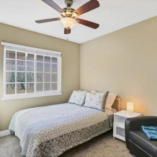 A cozy bedroom with a bed, ceiling fan, and a window.