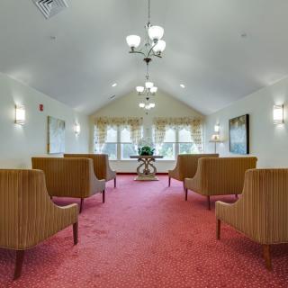 A neatly arranged lounge with chairs on a carpeted floor and elegant lighting.