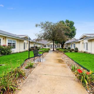 A landscaped pathway with benches leads through a garden area between residential buildings.