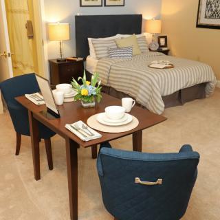 A cozy bedroom setup featuring a bed and a small dining table with two chairs.