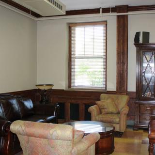 A cozy living room with sofas and armchairs, featuring a wooden coffee table and window.