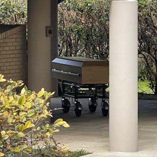 A casket on a cart in an outdoor area near a hospital.