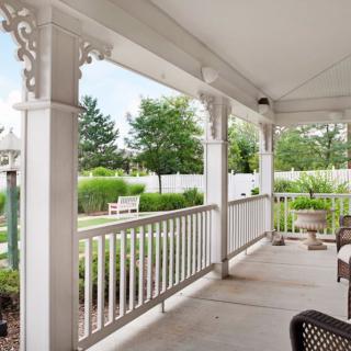 A peaceful porch overlooking a lush garden and white picket fence.