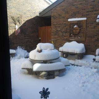 A serene winter scene featuring a snow-covered outdoor seating area.