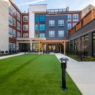 A modern residential building with a spacious courtyard featuring a well-maintained lawn.