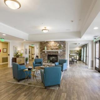 A modern lobby with a cozy seating area featuring blue chairs and a fireplace.