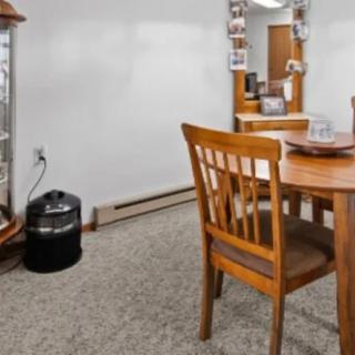 A dining area featuring a wooden table and chairs, with a mirror on the wall and carpeted flooring.