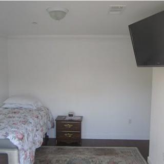 A minimalist bedroom with a single bed, nightstand, and wall-mounted TV.