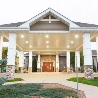 A welcoming building entrance with a covered walkway and landscaped surroundings.