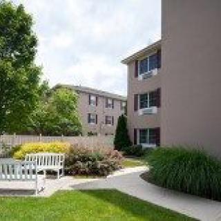 A well-maintained apartment complex with a landscaped garden and benches.