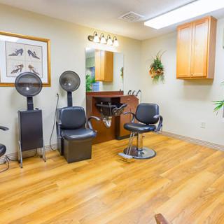 A cozy hair salon interior with styling chairs, dryers, and a mirror.