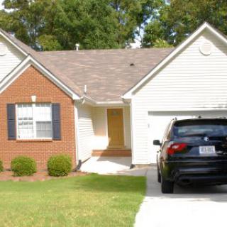 A suburban house with a brick facade and a car parked in the driveway.