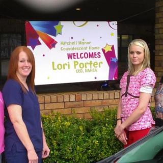 Group of people standing in front of a welcome sign.