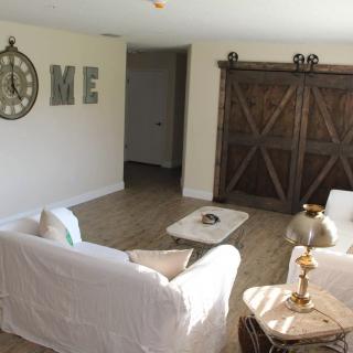 A cozy living room with farmhouse decor, featuring a large barn door and stylish furnishings.