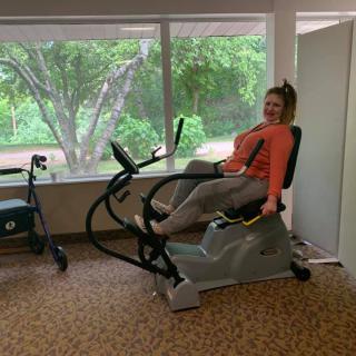 A person enjoying a workout session on a stationary bike in a brightly lit room with a scenic window view.